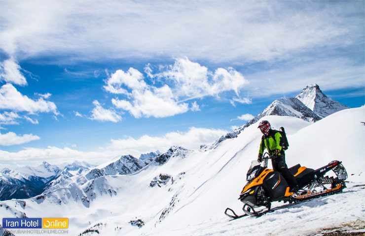 تصویری از گردشگر سوار بر اسنوموبیل در روز آفتابی